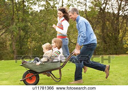 Stock Photograph - Parents Giving Children Ride In Wheelbarrow. Fotosearch