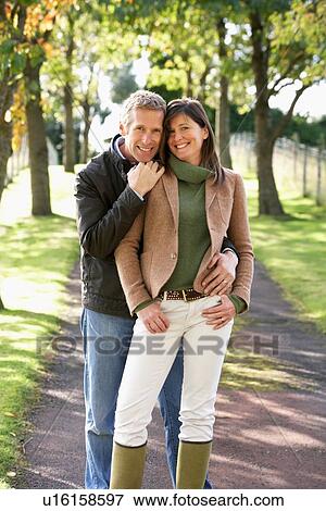 Stock Photo - Portrait Of Romantic Couple Enjoying Outdoor Walk Through Autumn Park. Fotosearch