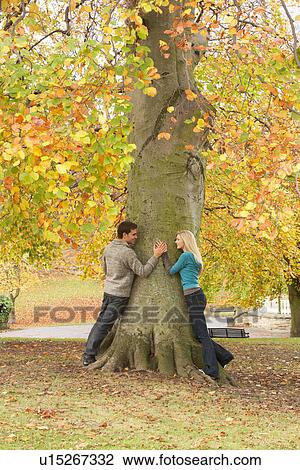 Stock Image - Romantic Teenage Couple By Tree In Autumn Park. Fotosearch