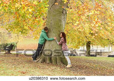 Stock Image - Romantic Teenage Couple By Tree In Autumn Park. Fotosearch