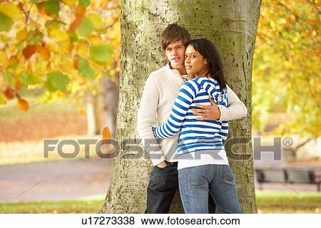 Stock Photo - Romantic Teenage Couple By Tree In Autumn Park. Fotosearch