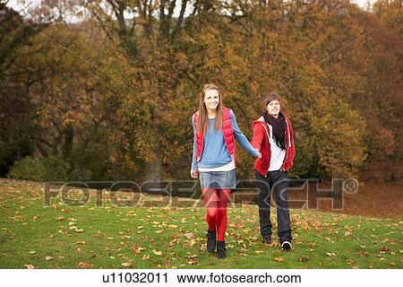 Stock Image - Romantic Teenage Couple Walking Through Autumn Landscape. Fotosearch