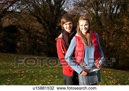 Stock Image - Romantic Teenage Couple Walking Through Autumn Landscape. Fotosearch