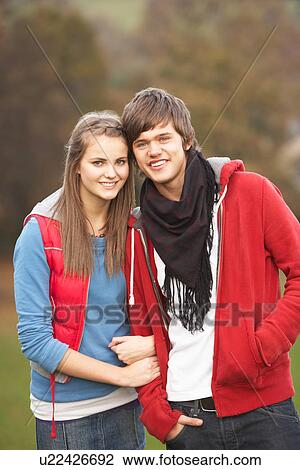 Stock Image - Romantic Teenage Couple Walking Through Autumn Landscape. Fotosearch