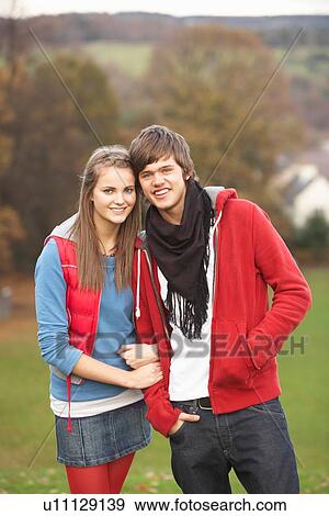 Stock Photo - Romantic Teenage Couple Walking Through Autumn Landscape. Fotosearch