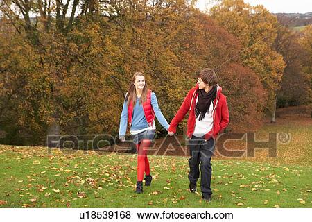Stock Photo - Romantic Teenage Couple Walking Through Autumn Landscape. Fotosearch