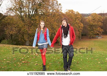 Stock Photography - Romantic Teenage Couple Walking Through Autumn Landscape. Fotosearch