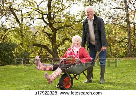 Stock Photo - Senior Couple Man Giving Woman Ride In Wheelbarrow. Fotosearch