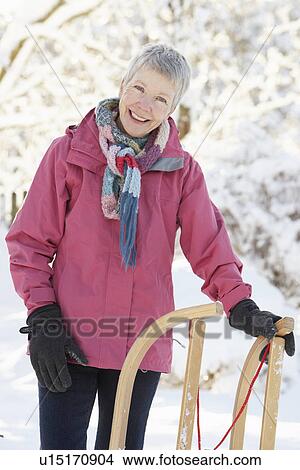 Picture - Senior Woman Holding Sledge In Snowy Landscape. Fotosearch