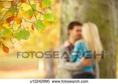 Stock Image - Shallow Focus View Of Romantic Teenage Couple By Tree In Autumn Park. Fotosearch