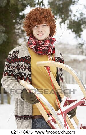 Stock Photography - Teenage Boy Holding Sledge In Snowy Landscape. Fotosearch