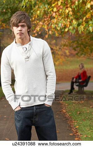 Teenage Boy Standing In Autumn Park With Female Figure On Bench In Background View Large Photo Image Stock Photo - Teenage Boy Standing In Autumn Park With Female Figure On Bench In Background. Fotosearch