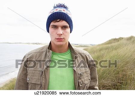 Stock Photography - Teenage Boy Standing In Sand Dunes Wearing Woolly Hat. Fotosearch