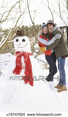 Picture - Teenage Couple Building Snowman. Fotosearch