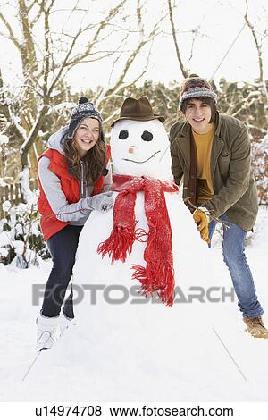 Stock Photo - Teenage Couple Building Snowman. Fotosearch