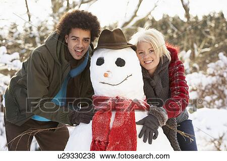 Teenage Couple Building Snowman View Large Photo Image Stock Photo - Teenage Couple Building Snowman. Fotosearch