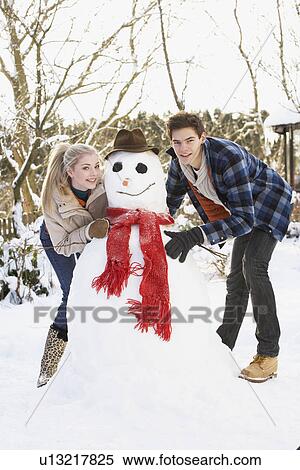 Teenage Couple Building Snowman View Large Photo Image Stock Photography - Teenage Couple Building Snowman. Fotosearch