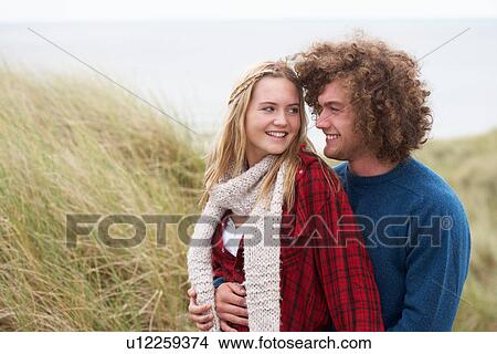 Teenage Couple Walking Through Sand Dunes Wearing Warm Clothing View Large Photo Image Picture - Teenage Couple Walking Through Sand Dunes Wearing Warm Clothing. Fotosearch