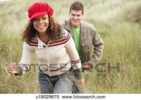 Teenage Couple Walking Through Sand Dunes Wearing Warm Clothing View Large Photo Image Stock Photography - Teenage Couple Walking Through Sand Dunes Wearing Warm Clothing. Fotosearch