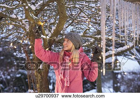 Stock Photo - Teenage Girl Hanging Fairy Lights In Tree With Icicles In Foreground. Fotosearch