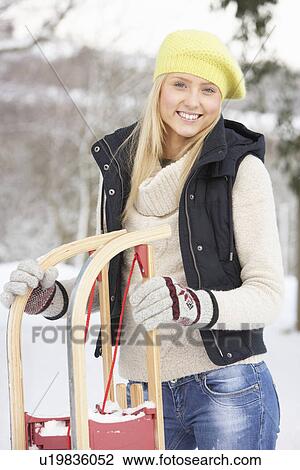 Stock Image - Teenage Girl Holding Sledge In Snowy Landscape. Fotosearch
