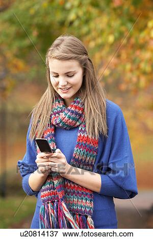 Stock Photo - Teenage Girl Making Mobile Phone Call In Autumn Landscape. Fotosearch