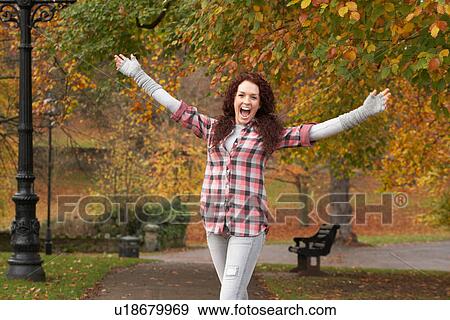 Stock Photo - Teenage Girl Standing In Autumn Park With Arms Outstretched. Fotosearch