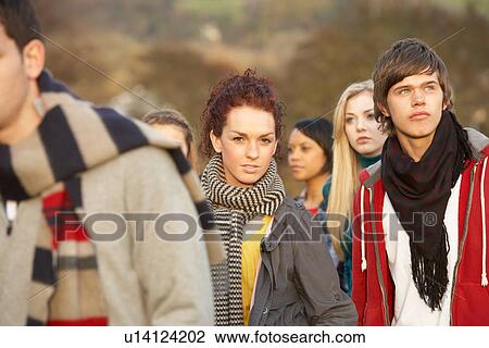 Stock Image - Teenage Girl Surrounded By Friends In Outdoor Autumn Landscape. Fotosearch