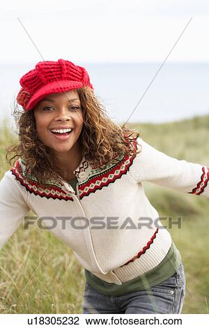 Stock Image - Teenage Girl Walking Through Sand Dunes Wearing Warm Clothing. Fotosearch