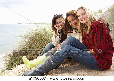 Picture - Three Teenage Girls Sitting In Sand Dunes Together. Fotosearch