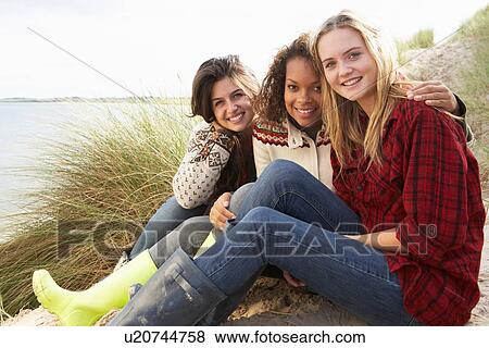 Stock Photo - Three Teenage Girls Sitting In Sand Dunes Together. Fotosearch