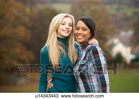 Stock Image - Two Female Teenage Friends On Walk In Autumn Landscape. Fotosearch