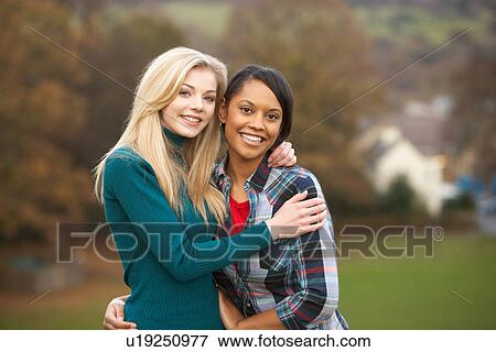 Stock Photo - Two Female Teenage Friends On Walk In Autumn Landscape. Fotosearch