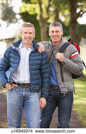 Picture - Two Male Friends Walking Outdoors In Autumn Park Together. Fotosearch