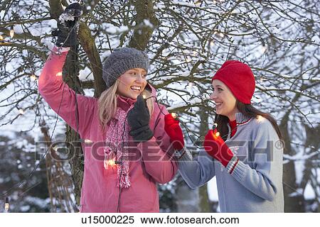 Two Teenage Girls Hanging Fairy Lights In Tree With Icicles In Foreground View Large Photo Image Stock Photography - Two Teenage Girls Hanging Fairy Lights In Tree With Icicles In Foreground. Fotosearch