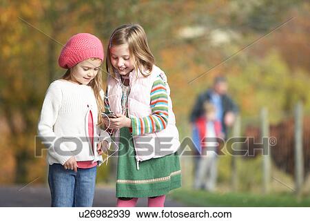 Two Young Girl Listening To MP3 Player Outdoors View Large Photo Image Stock Photo - Two Young Girl Listening To MP3 Player Outdoors. Fotosearch
