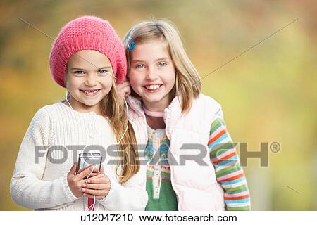 Stock Image - Two Young Girl Outdoors With MP3 Player. Fotosearch