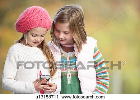 Stock Image - Two Young Girl Outdoors With MP3 Player. Fotosearch