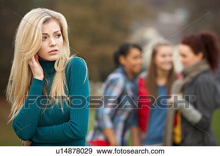 Stock Photo - Upset Teenage Girl With Friends Gossiping In Background. Fotosearch