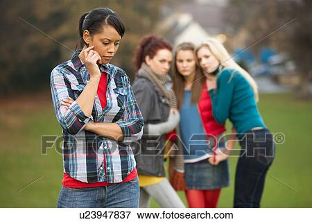 Upset Teenage Girl With Friends Gossiping In Background View Large Photo Image Stock Photo - Upset Teenage Girl With Friends Gossiping In Background. Fotosearch