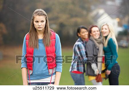 Stock Photo - Upset Teenage Girl With Friends Gossiping In Background. Fotosearch