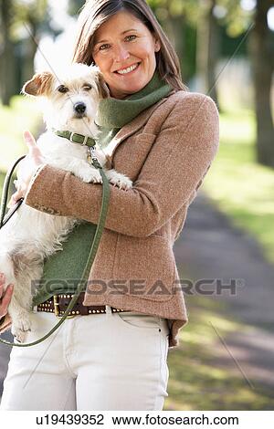 Stock Image - Woman Walking Dog Outdoors In Autumn Park. Fotosearch