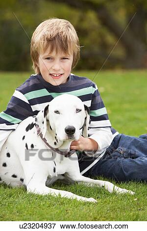 Stock Photo - Young Boy Relaxing Outdoors With Pet Dog. Fotosearch