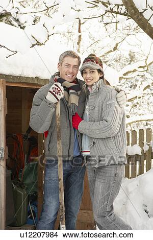 Picture - Young Couple Clearing Snow From Path To Wooden Store. Fotosearch