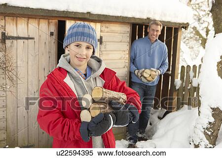 Stock Photography - Young Couple Collecting Logs From Wooden Store In Snow. Fotosearch