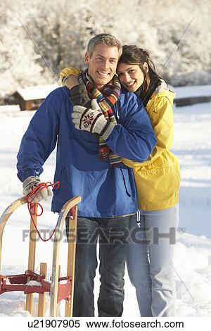 Young Couple Standing In Snowy Landscape Holding Sledge View Large Photo Image Stock Photography - Young Couple Standing In Snowy Landscape Holding Sledge. Fotosearch