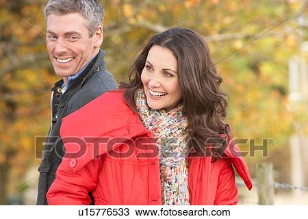 Stock Image - Young Couple Walking Through Autumn Park. Fotosearch