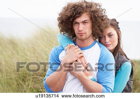Picture - Young Couple Walking Through Sand Dunes Wearing Warm Clothing. Fotosearch