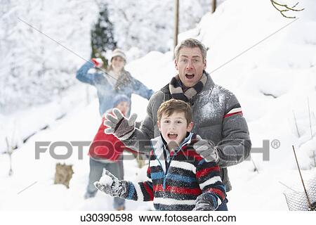 Stock Photo - Young Family Having Snowball Fight In Snowy Landscape. Fotosearch