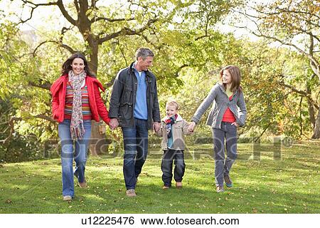 Stock Photograph - Young Family Outdoors Walking Through Park. Fotosearch